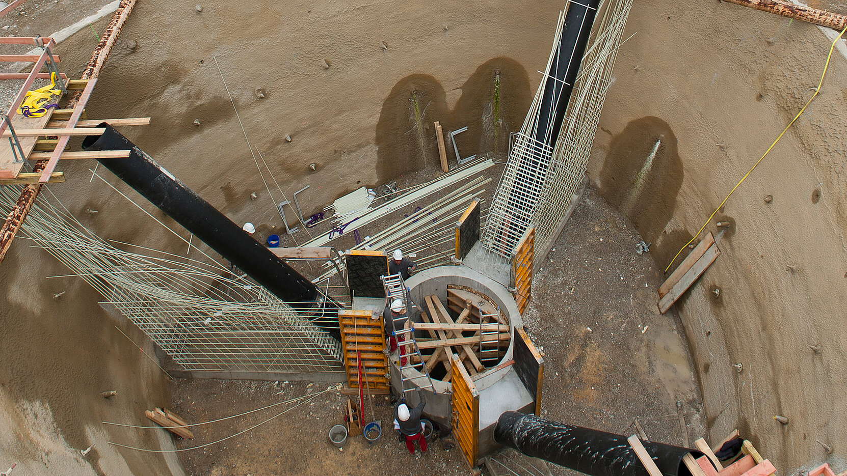 Luftbild der Baugrube mit Zentralschacht und Messrohren in den Wänden des Tetraeders.